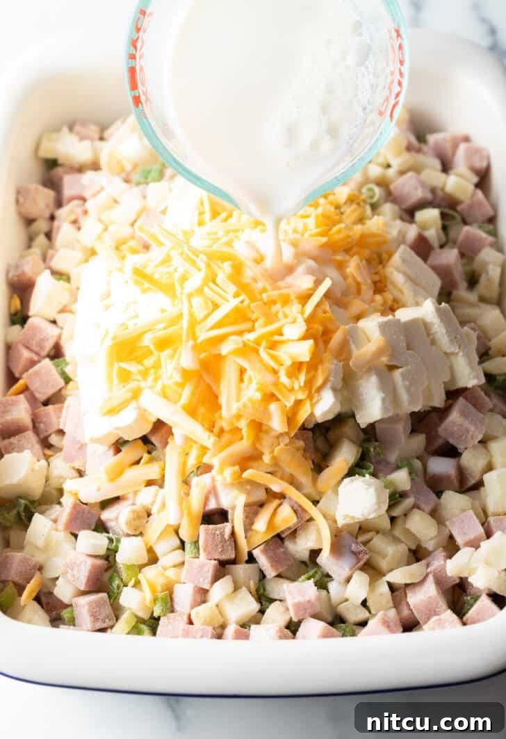 Golden Ham and Potato Bake 8 Adding milk to the chopped potatoes, ham, and shredded cheese in a casserole dish before baking.