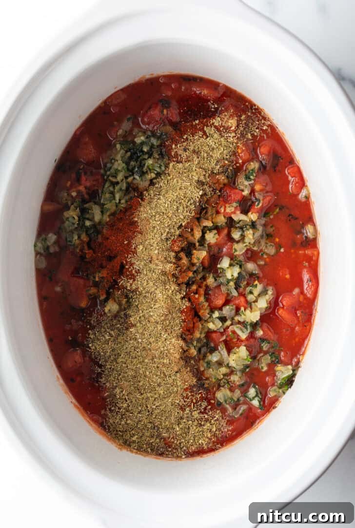 Fiesta Slow Cooker Chicken 7 Top down view white crock pot with salsa and cooked herbs.