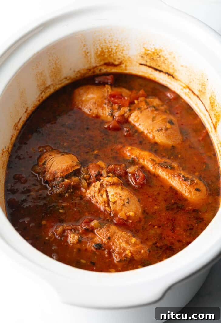 Fiesta Slow Cooker Chicken 9 Several whole chicken breasts covered in red sauce in a white crockpot.