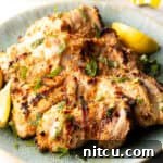 Grilled marinated chicken thighs in a shallow blue bowl.