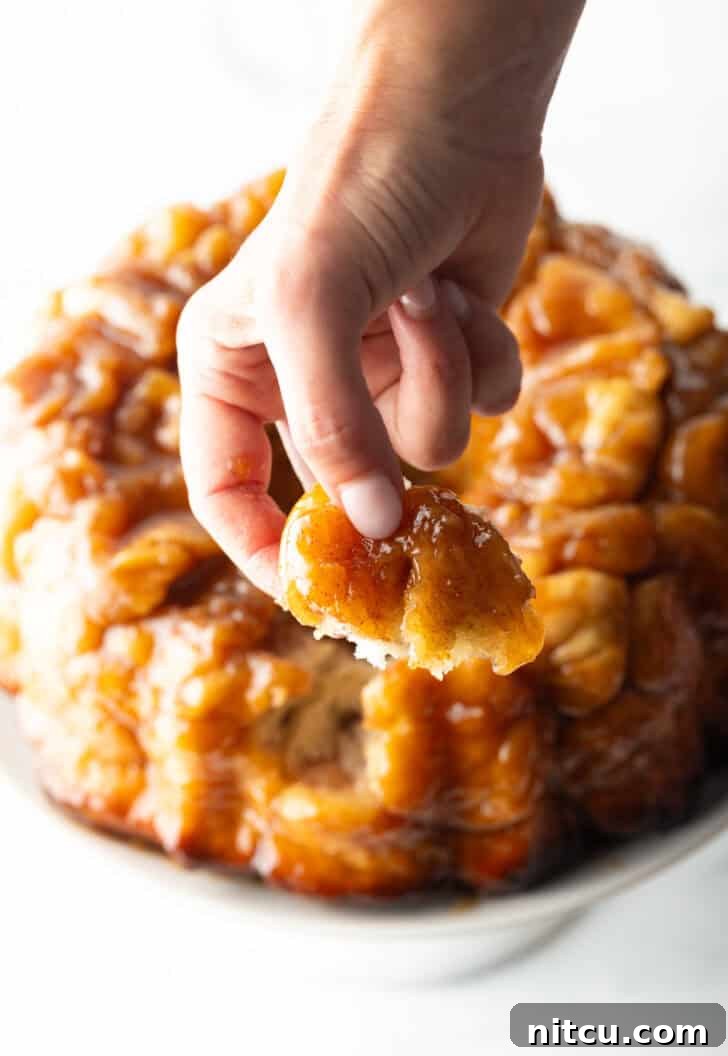 Irresistible Monkey Bread Delight 15 Hand pulling a baked dough monkey ball from the loaf.