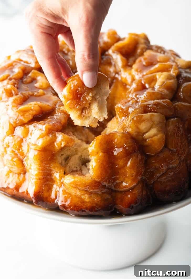 Irresistible Monkey Bread Delight 4 Hand pulling a baked dough monkey ball from the loaf.