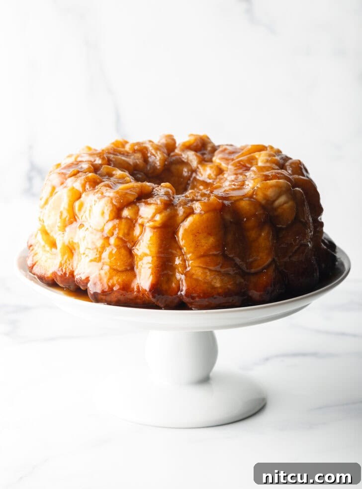 Irresistible Monkey Bread Delight 5 Monkey bread baked in a bundt pan, plated on a white cake stand.