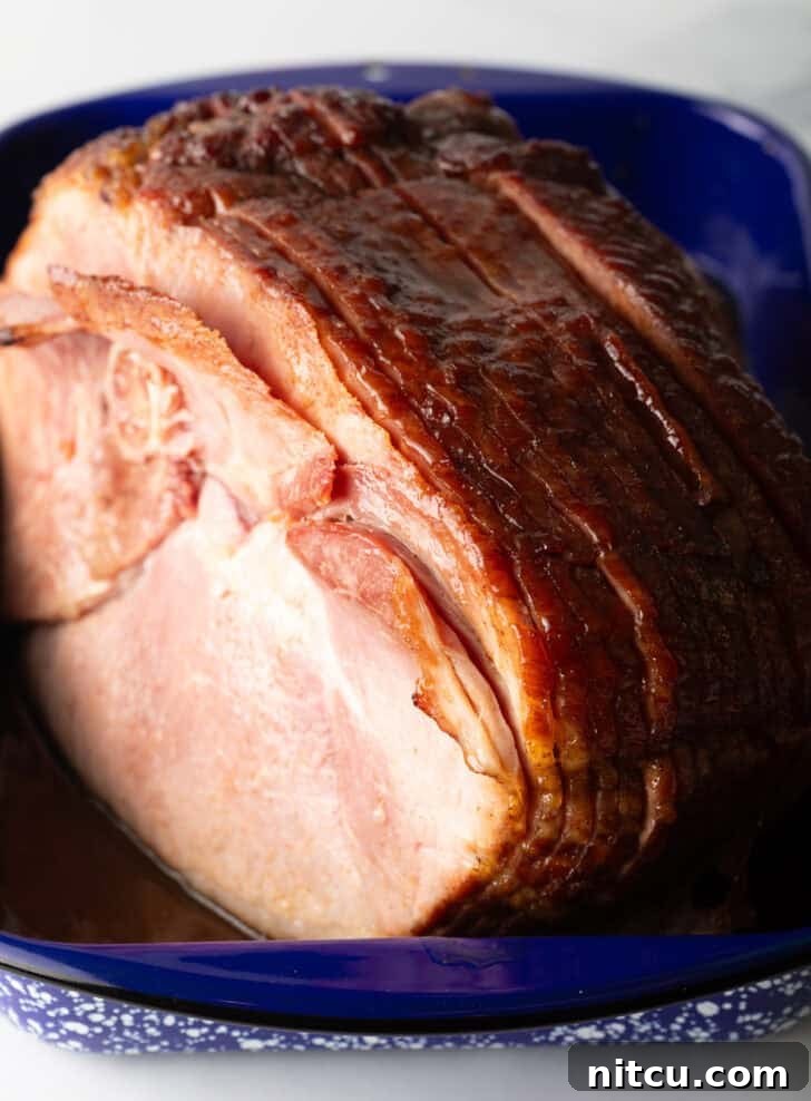 Perfect Spiral Ham Recipe 2 A beautifully cooked spiral ham, glistening with glaze, resting in a blue and white speckled roasting pan, ready to be carved and enjoyed.