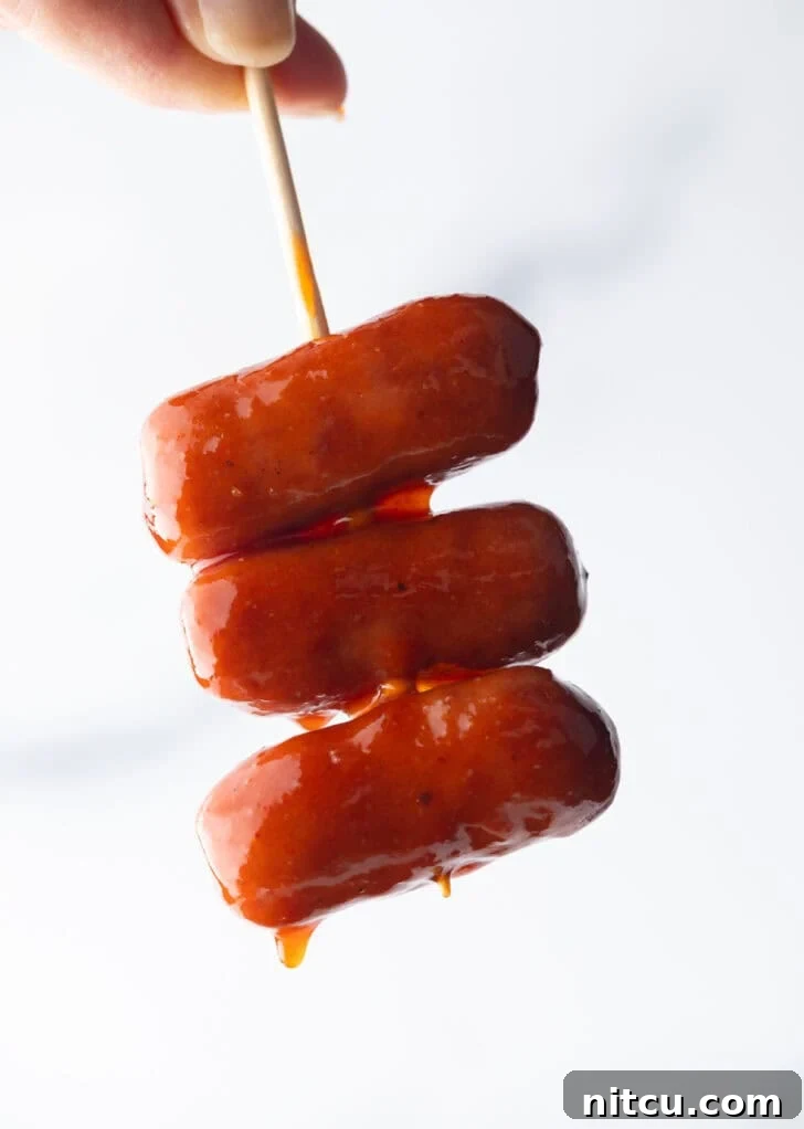 Glazed Cocktail Smokies 4 Hand holding a skewer with 3 little smokies.