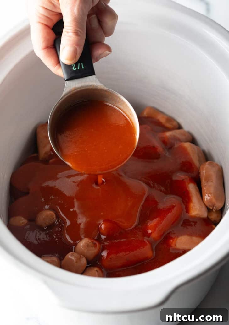 Glazed Cocktail Smokies 6 Hand pouring hot sauce from a measuring cup into a slow cooker with smokies.