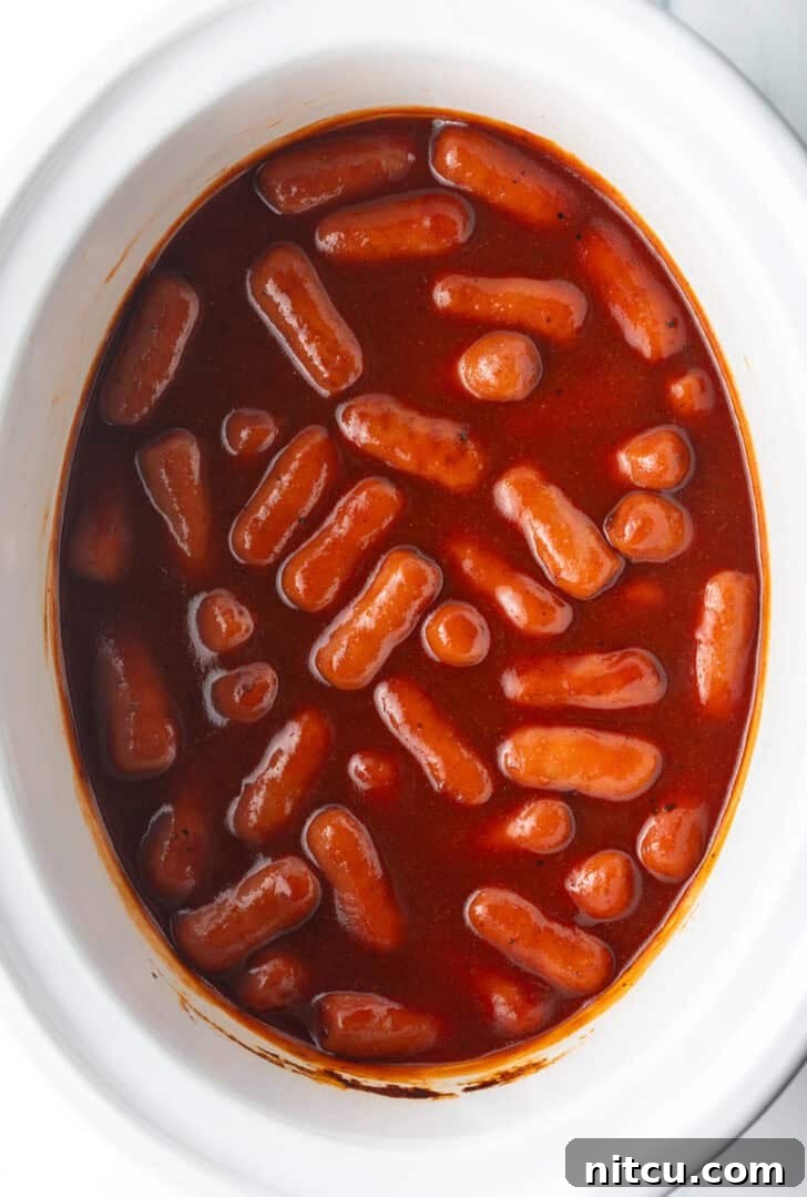 Glazed Cocktail Smokies 10 Top down view little smokies in barbecue sauce in a white crock pot.