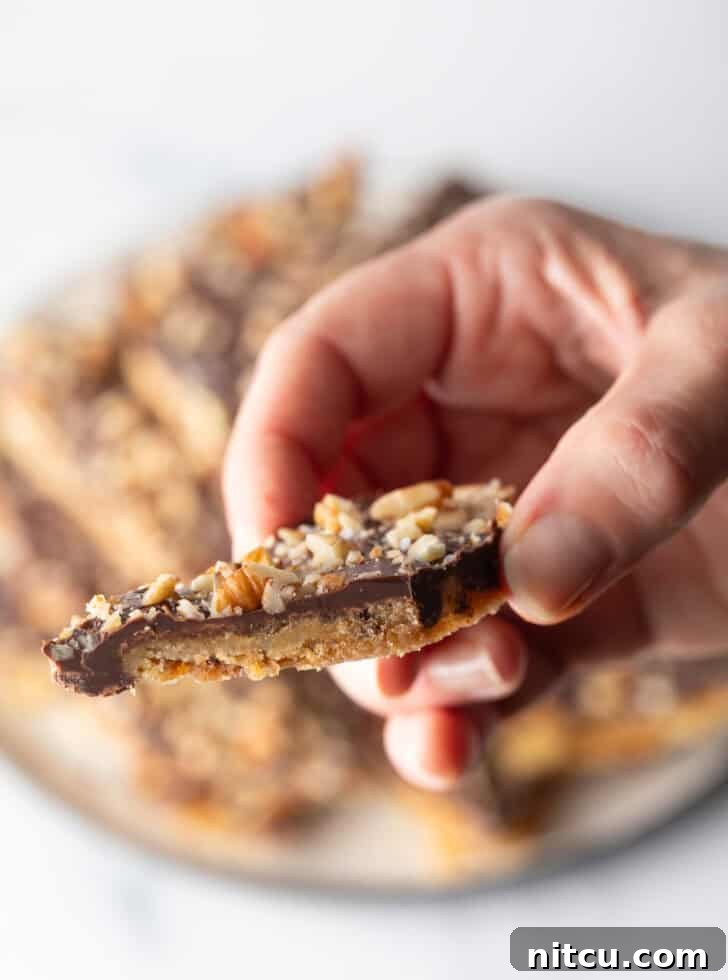 Hand holding a piece of saltine toffee aka Christmas crack.