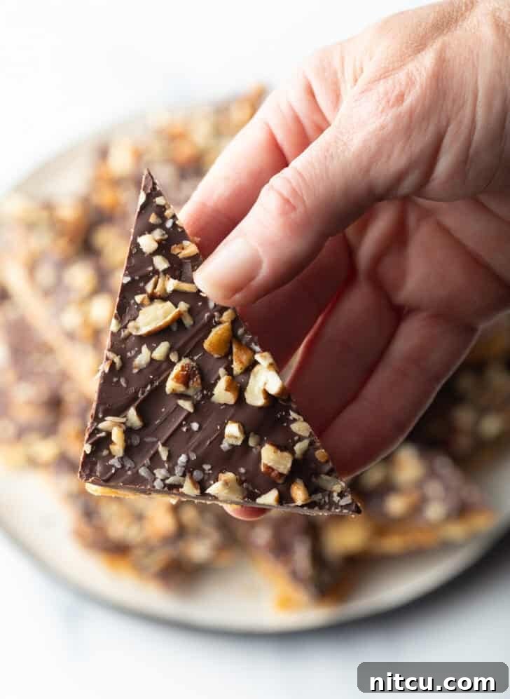 Hand holding a piece of saltine toffee aka Christmas crack.