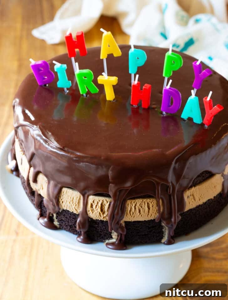 Ultimate Ice Cream Cake 12 Chocolate and caramel ice cream layered cream cake coated with glossy icing and Happy Birthday candles on top.