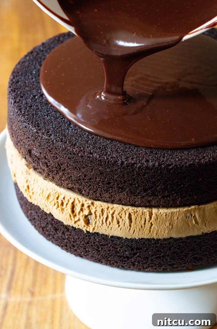Ultimate Ice Cream Cake 10 Pouring melted fudge frosting overtop a chocolate and caramel layered ice cream cake.