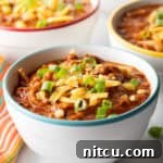 Easy 5 Ingredient Chicken Chili 14 A bowlful of rich chicken chili, beautifully topped with fresh chopped green onion and a generous portion of shredded cheddar cheese, ready to be enjoyed.