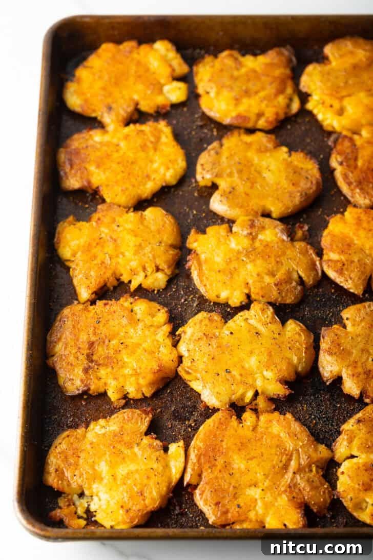Crispy Smashed Potatoes 11 15 golden smashed potatoes on a baking sheet.