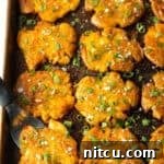 Crispy Smashed Potatoes 14 Top down view of 15 golden smashed potatoes on a baking sheet.