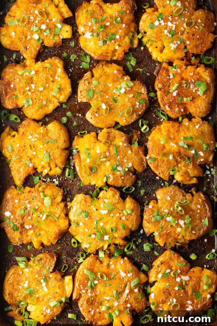 Crispy Smashed Potatoes 4 Top down view of 15 golden smashed potatoes on a baking sheet.
