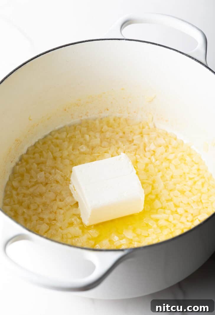 Chunk of butter melting in a pan with diced onions.