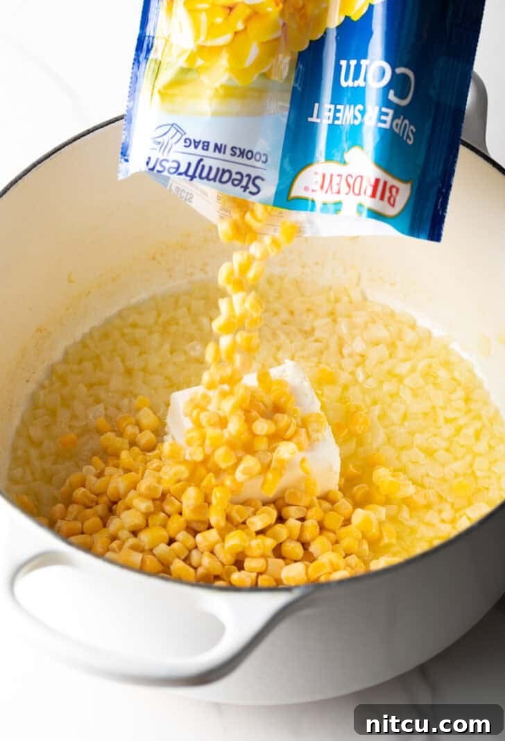 Adding frozen corn from a bag into a large pot of corn with butter and onions.