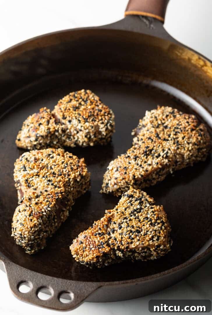 Flash-Seared Ahi Tuna 11 Four perfectly crusted yellowfin tuna steaks searing in a hot cast iron pan, forming a beautiful crust.