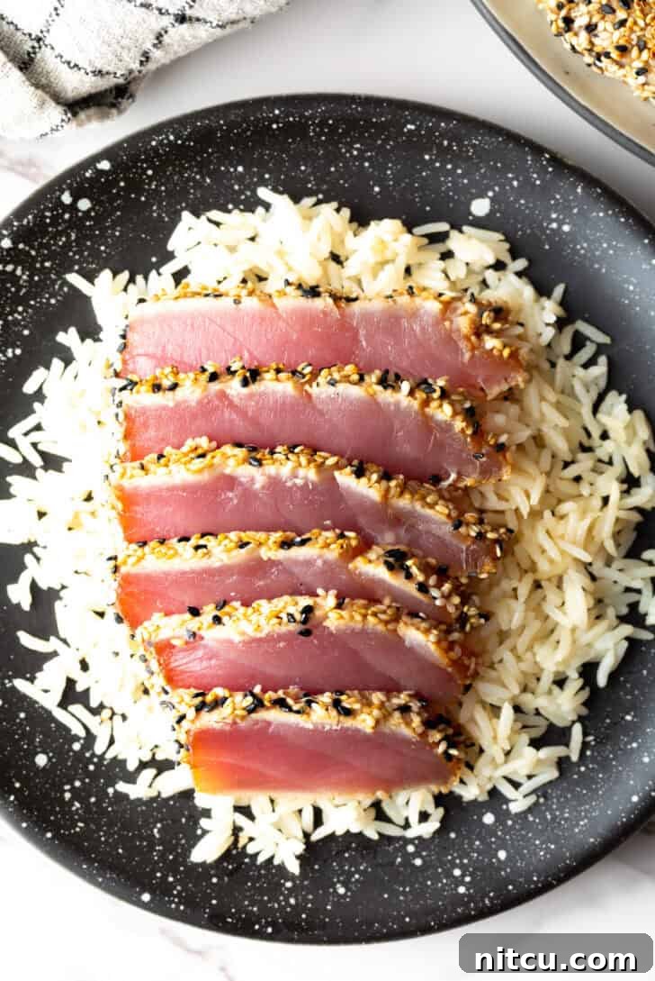 Flash-Seared Ahi Tuna 13 Top-down view of six perfectly seared ahi tuna slices presented elegantly on a bed of fluffy white rice.