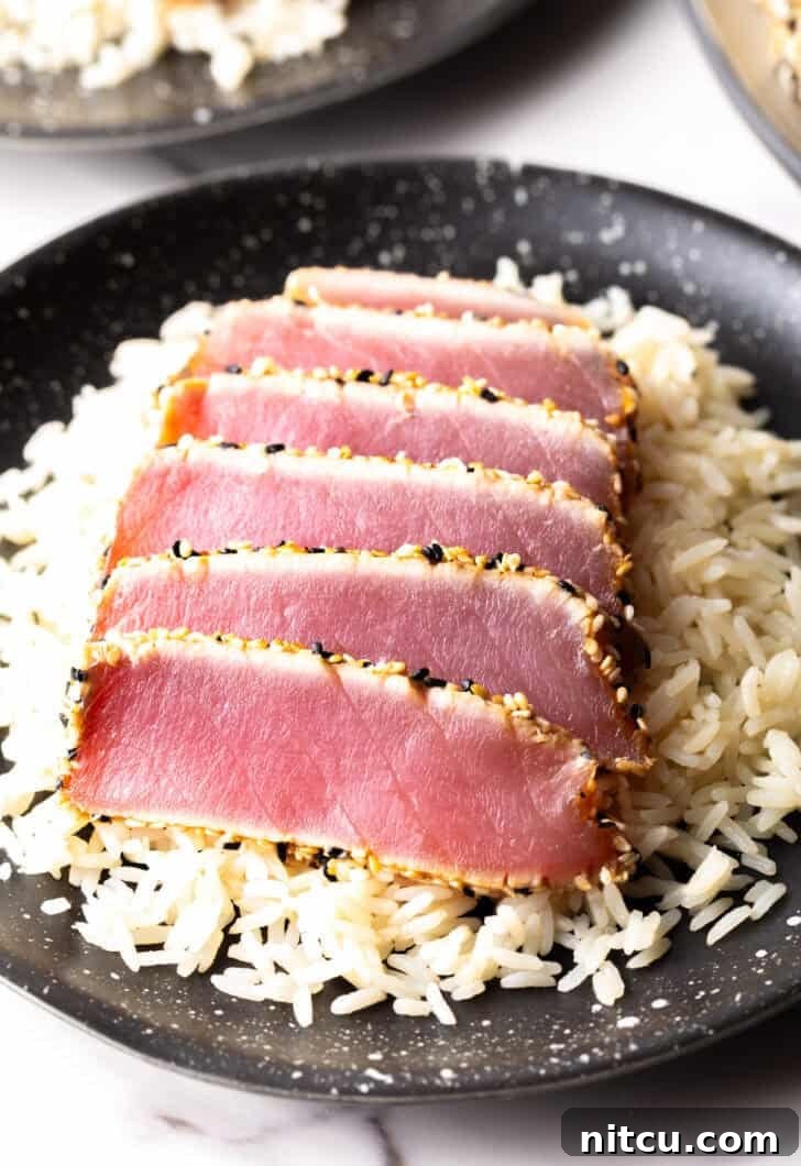 Flash-Seared Ahi Tuna 4 Six perfectly seared ahi tuna slices arranged on a bed of fluffy white rice.