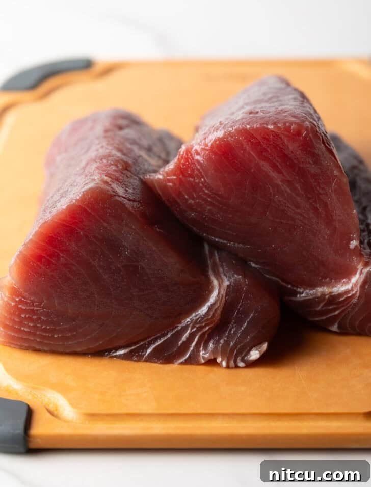 Flash-Seared Ahi Tuna 6 Two large pieces of raw yellowfin tuna on a cutting board, ready to be sliced.