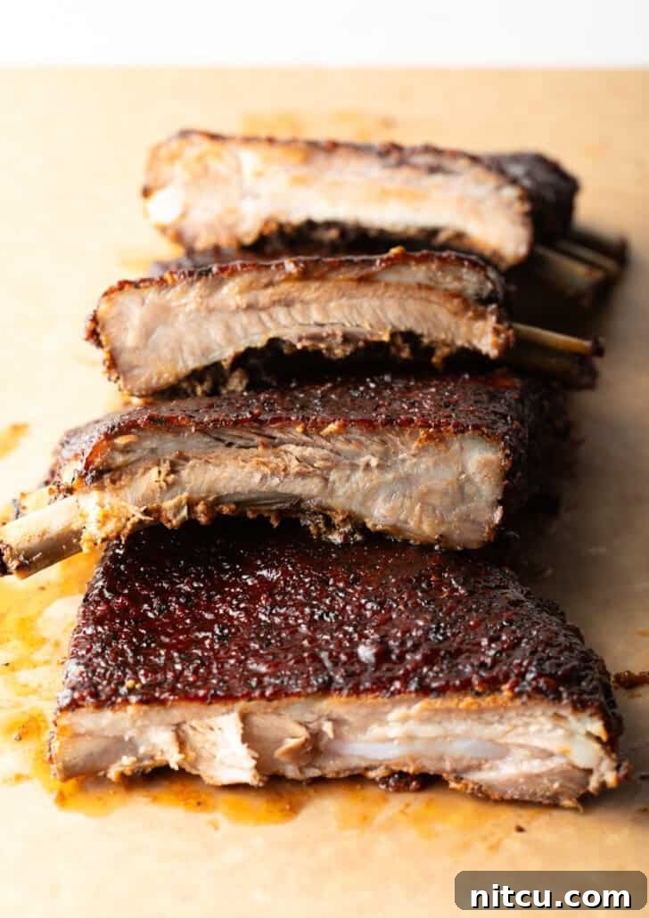 Gateway City Ribs 2 Perfectly sliced St. Louis style ribs stacked on a wooden cutting board, ready to serve.