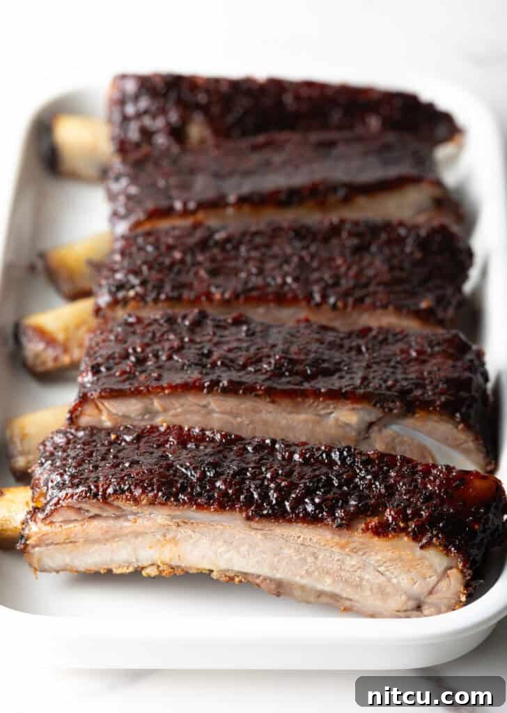 Gateway City Ribs 12 Six perfectly grilled barbecue pork ribs, neatly sliced and arranged on a white serving tray.