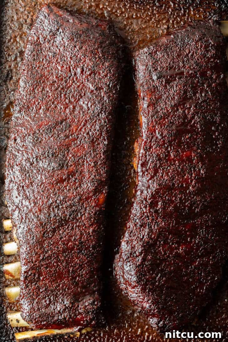 Gateway City Ribs 4 Two full racks of uncooked St. Louis pork ribs resting on a cooking tray.