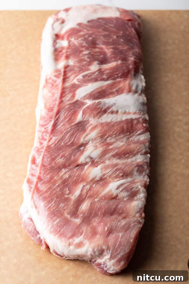 Gateway City Ribs 6 Overhead shot of a raw rack of pork ribs on a cutting board, ready for preparation.