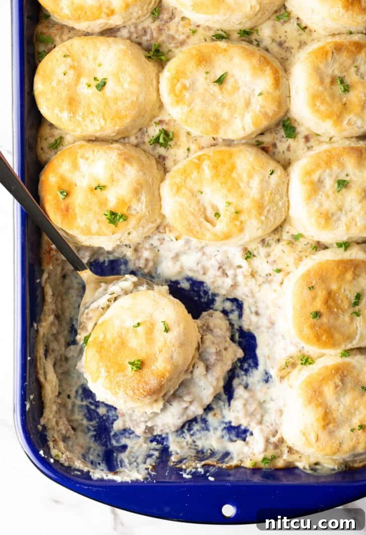 A large pan of biscuits with rich sausage gravy bubbling underneath.