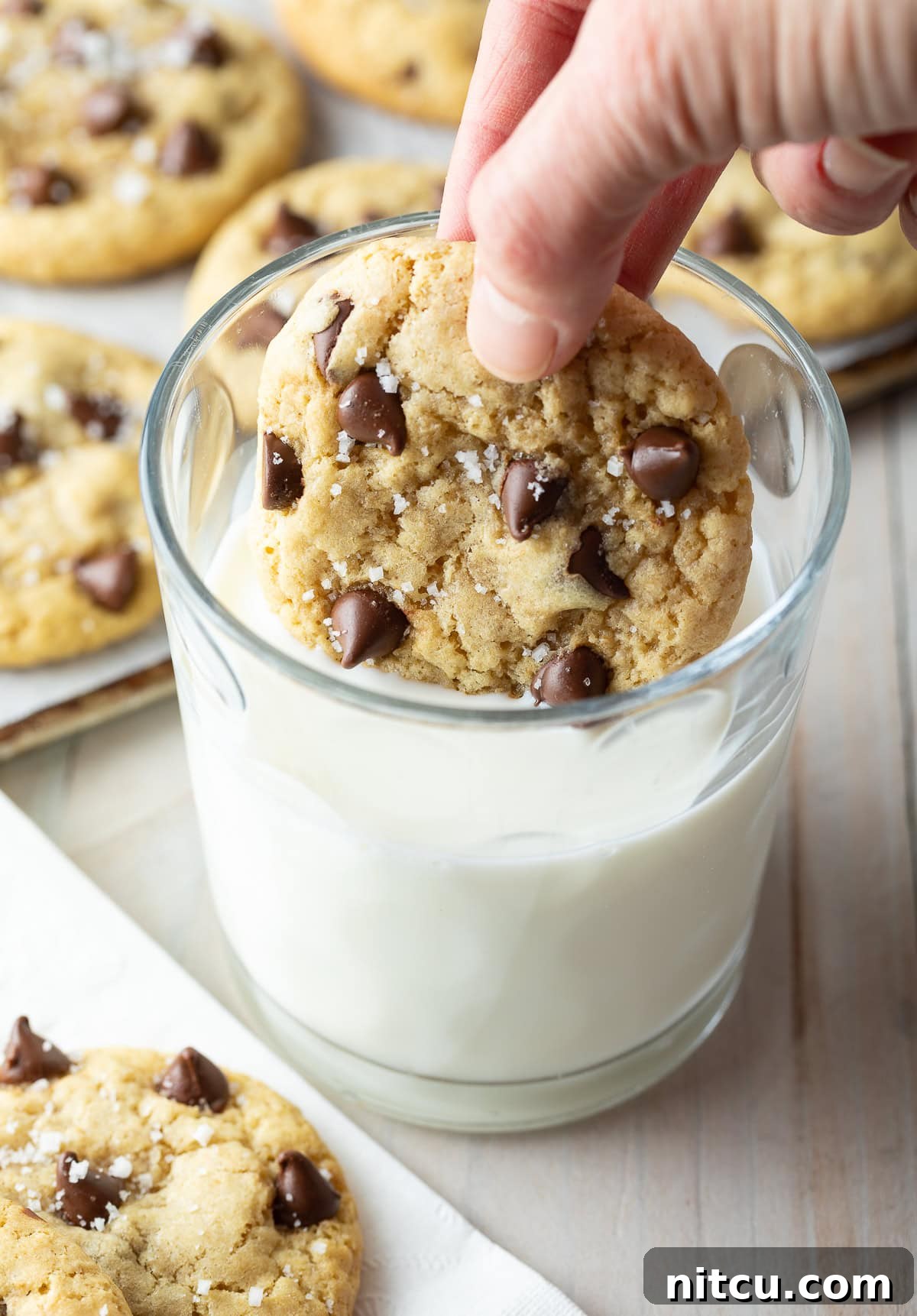 Salted Chocolate Chip Cookie Bliss 11 A hand dunking a freshly baked salted chocolate chip cookie into a refreshing glass of milk, a classic pairing.
