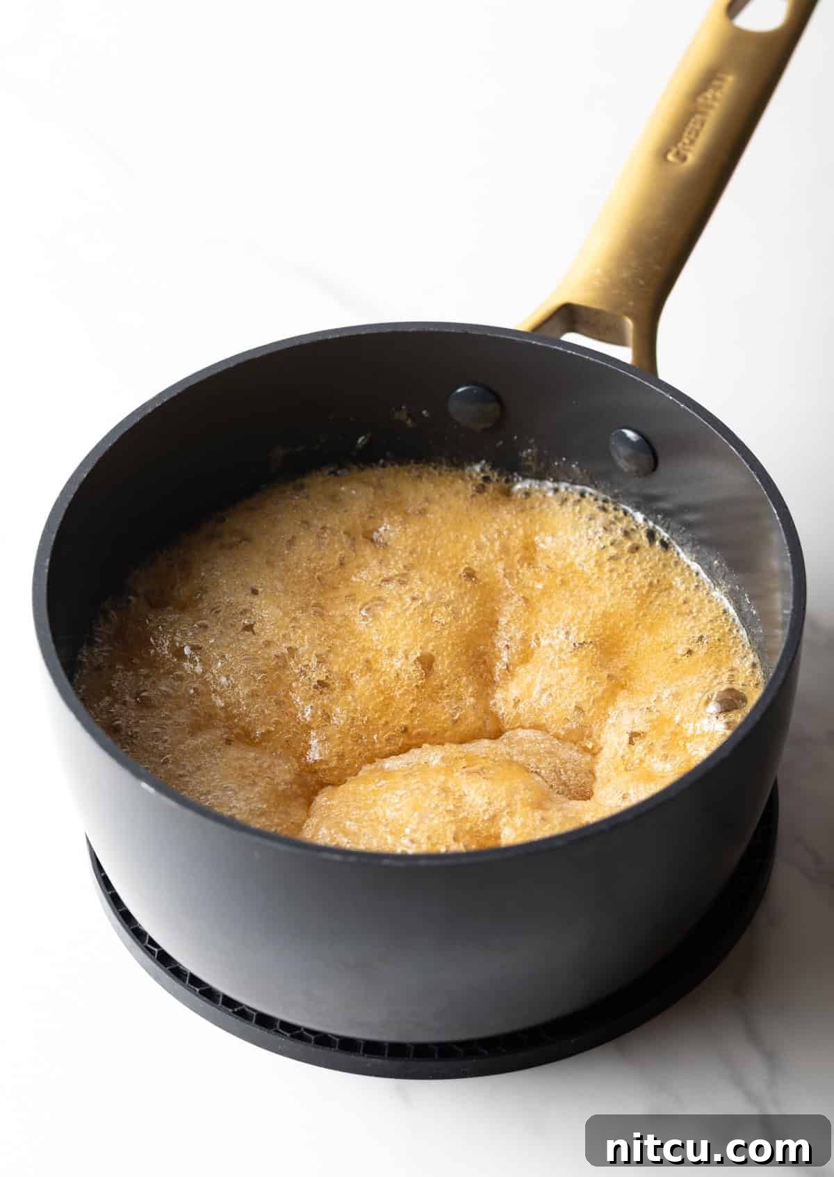 Salted Caramel Delight 6 A mixture of sugar and water bubbling in a black pan.