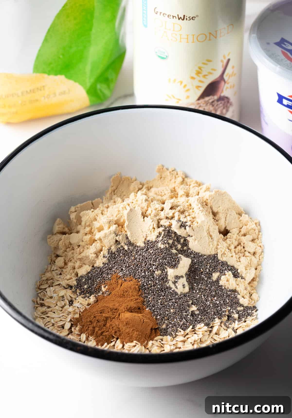 Protein Packed Next-Day Oats 6 Dry ingredients for high protein overnight oats recipe in a white bowl.