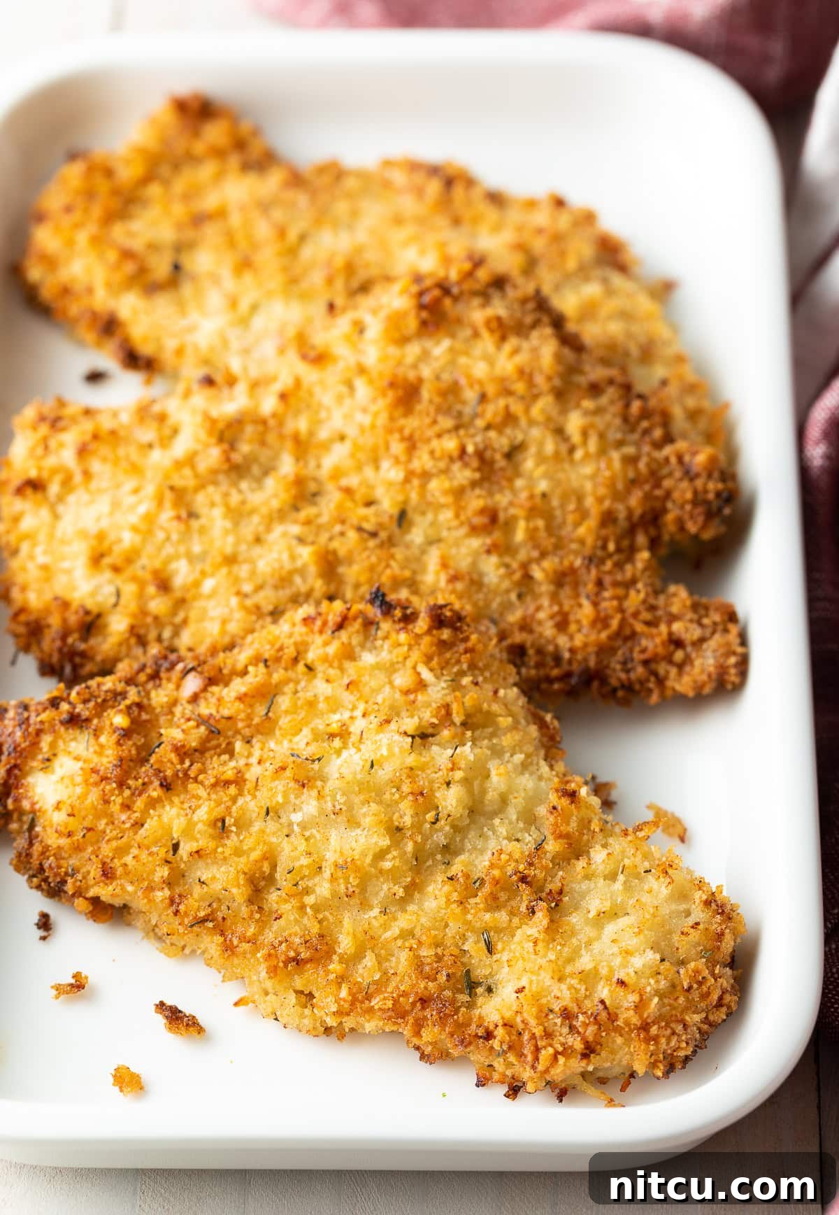 Golden Baked Chicken Cutlets 4 Close up of perfectly golden and crispy baked breaded chicken cutlets on a platter.