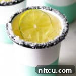 White and green-striped cup with salt around the rim and slice of lime in the drink.
