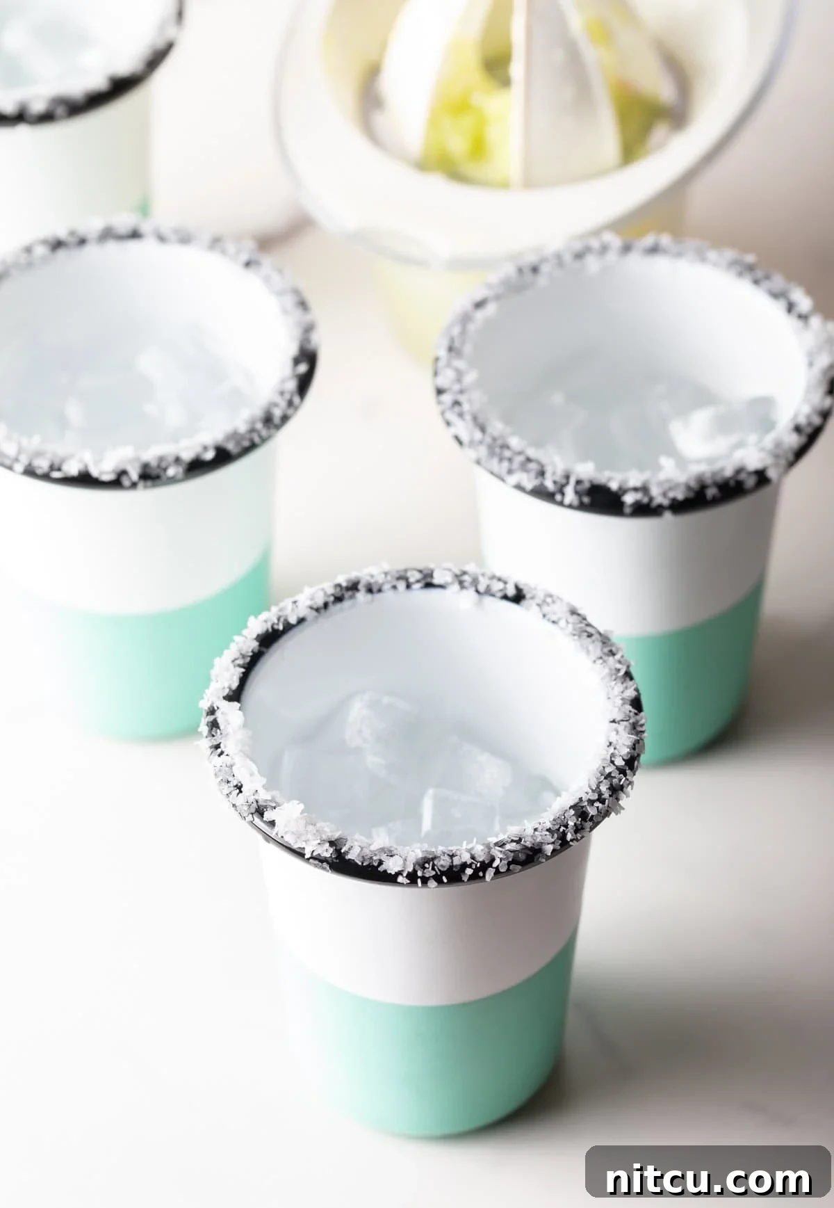 Zero-Proof Margarita 6 4 blue and white striped cups, with salt around the rim.