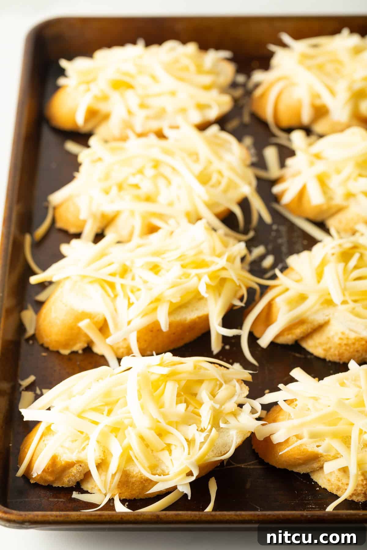 Smoky Red Pepper Bisque 11 A dozen golden-brown baguette slices, generously topped with melted and bubbly Gouda cheese, baked to perfection on a baking sheet, ready to be served.
