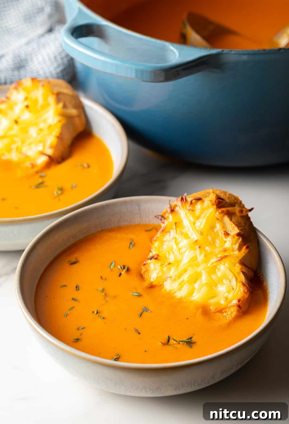 Smoky Red Pepper Bisque 14 A delectable bowl of roasted red pepper Gouda soup, rich and vibrant, with a perfectly toasted cheesy baguette slice nestled invitingly within.
