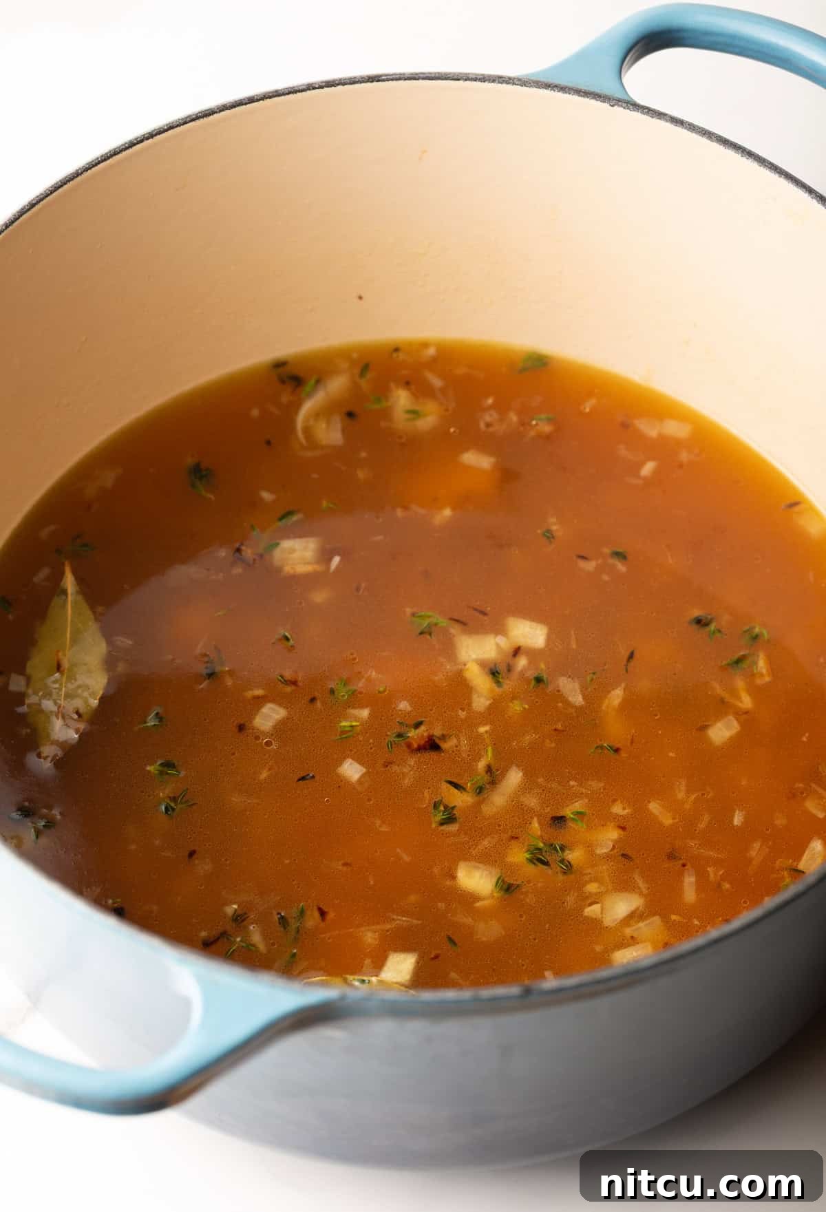 Smoky Red Pepper Bisque 8 A large soup pot containing a simmering blend of onions, garlic, broth, tomato paste, and herbs, forming the aromatic base for the roasted red pepper Gouda soup.