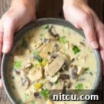 Creamy Chicken Mushroom Soup in bowl with hand holding the bowl