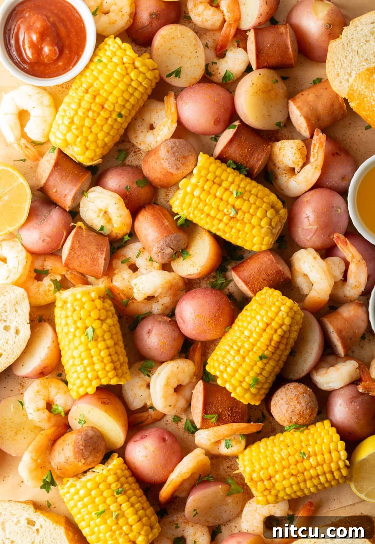 Coastal Bounty Boil 4 A vibrant display of fresh ingredients for a Low Country Boil, including raw shrimp, slices of smoked sausage, bright corn on the cob, and small red potatoes, all generously dusted with aromatic Old Bay seasoning, ready for cooking.