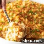 Big Easy Mac and Cheese 14 A spoon is scooping a serving of New Orleans style macaroni and cheese from a white dish.