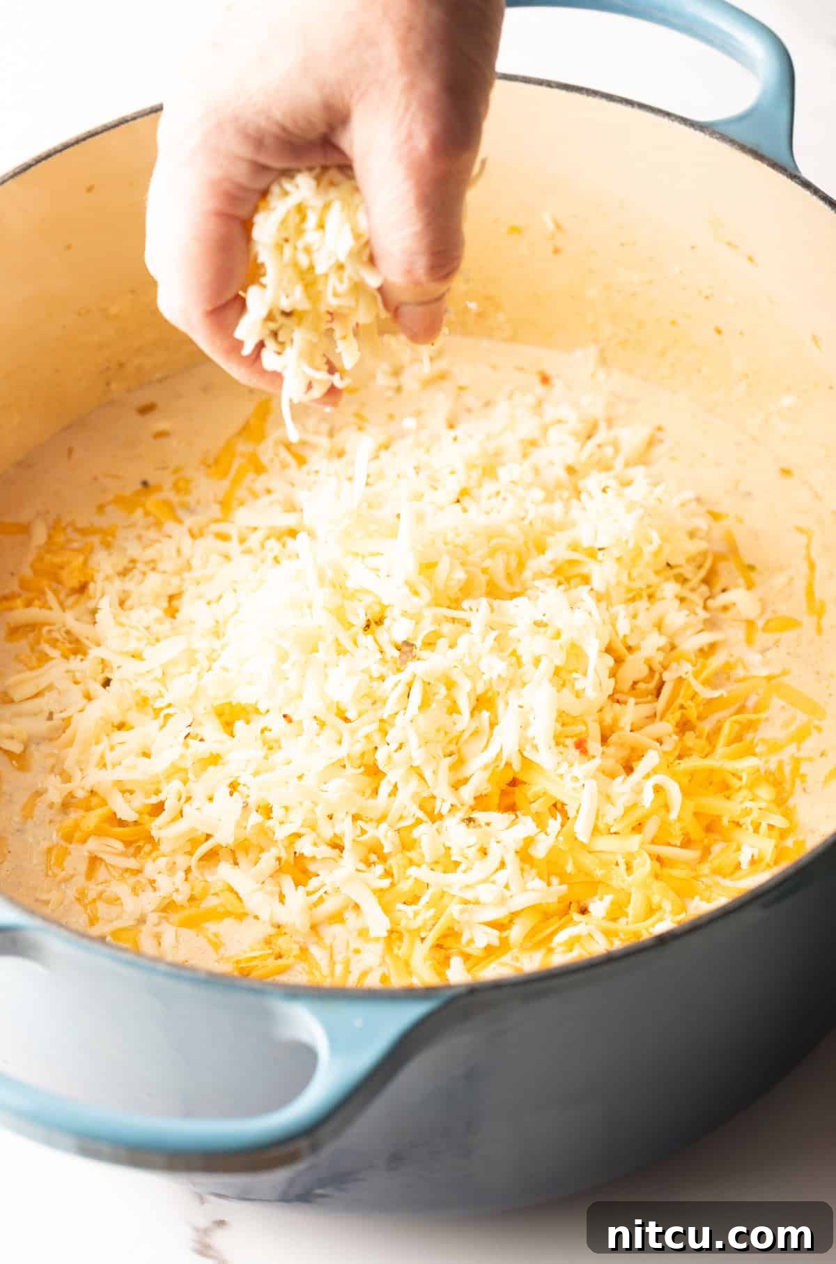 Big Easy Mac and Cheese 8 Grated cheese is being added to the cream mixture for Cajun style mac and cheese.