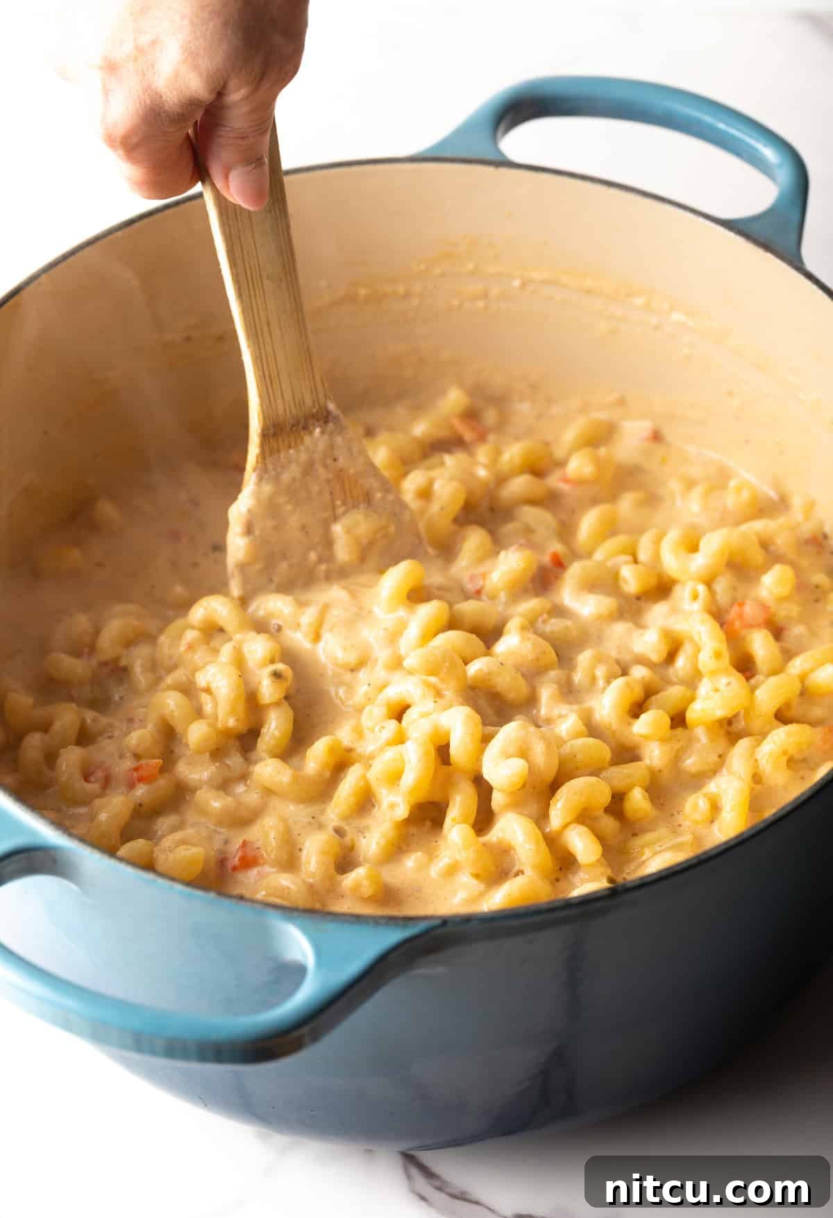 Big Easy Mac and Cheese 9 A wooden spoon is stirring pasta into the cheese sauce.
