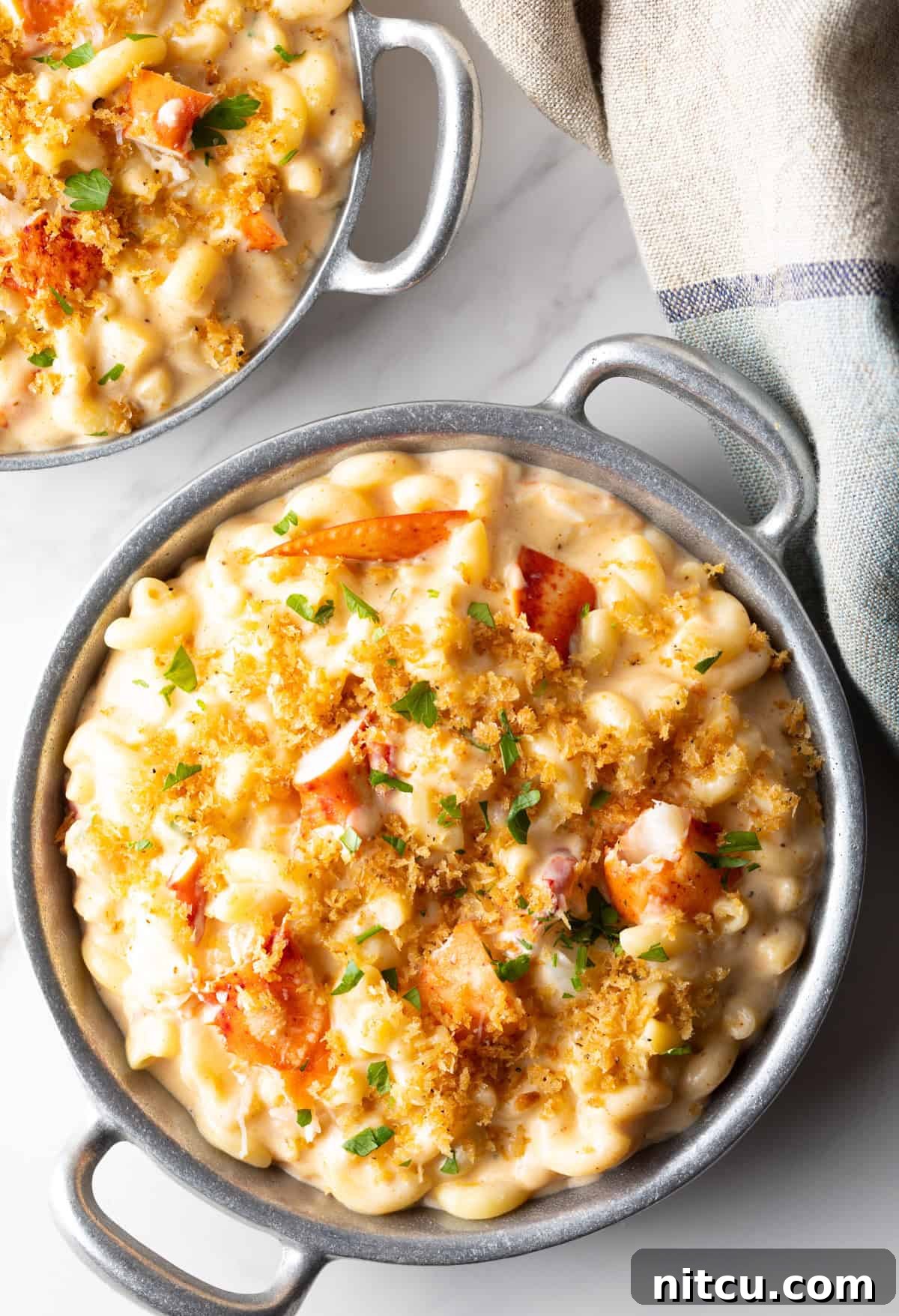 Decadent Lobster Mac and Cheese 2 Two metal bowls filled with creamy lobster mac and cheese.