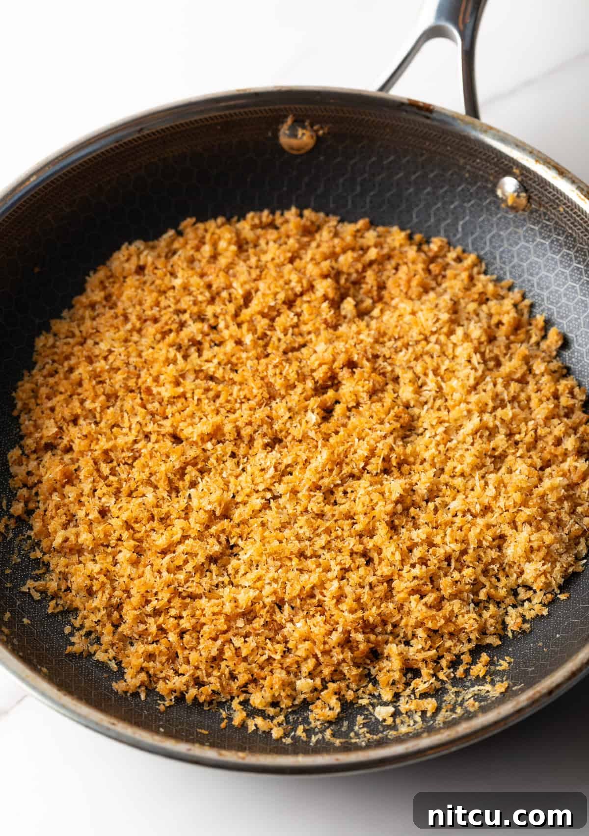 Decadent Lobster Mac and Cheese 7 Breadcrumbs are being toasted in a skillet.