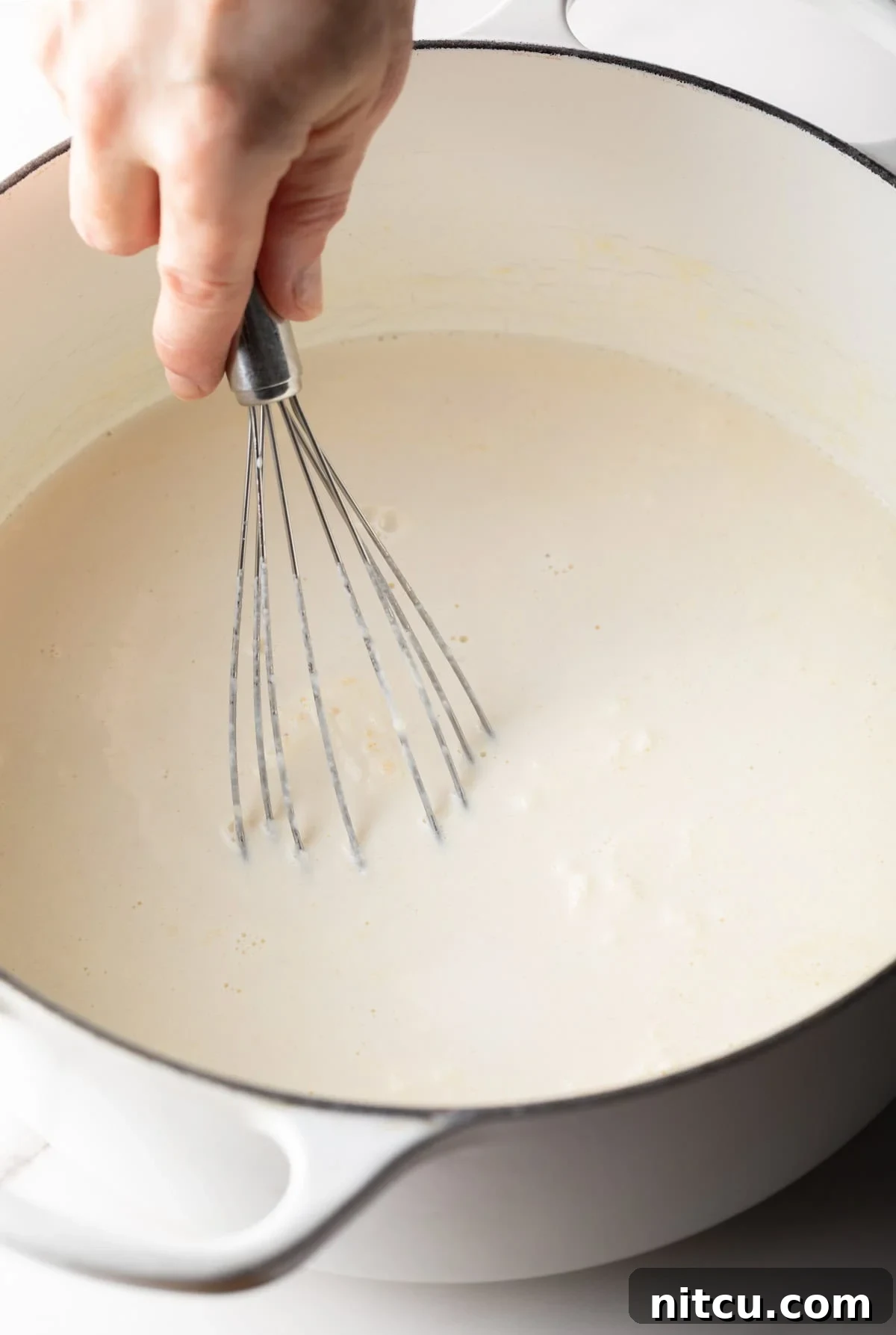Decadent Lobster Mac and Cheese 8 A whisk is whisking the roux and cream mixture for a lobster macaroni and cheese recipe.