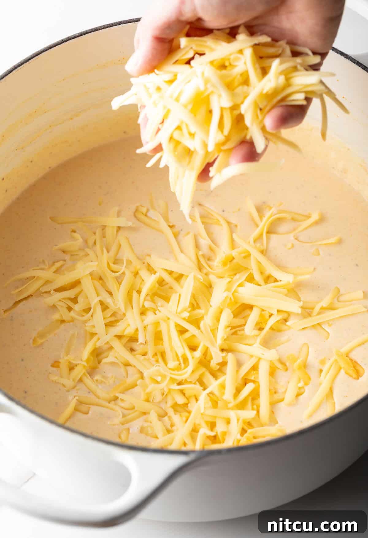 Decadent Lobster Mac and Cheese 9 Shredded cheese is being added to a cream sauce for lobster mac and cheese.