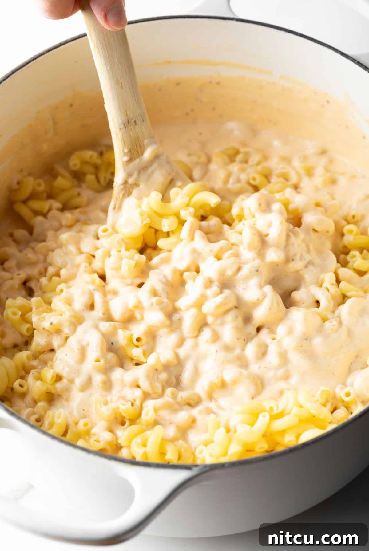 Decadent Lobster Mac and Cheese 10 Macaroni pasta is being stirred into the cheese sauce for lobster mac and cheese.