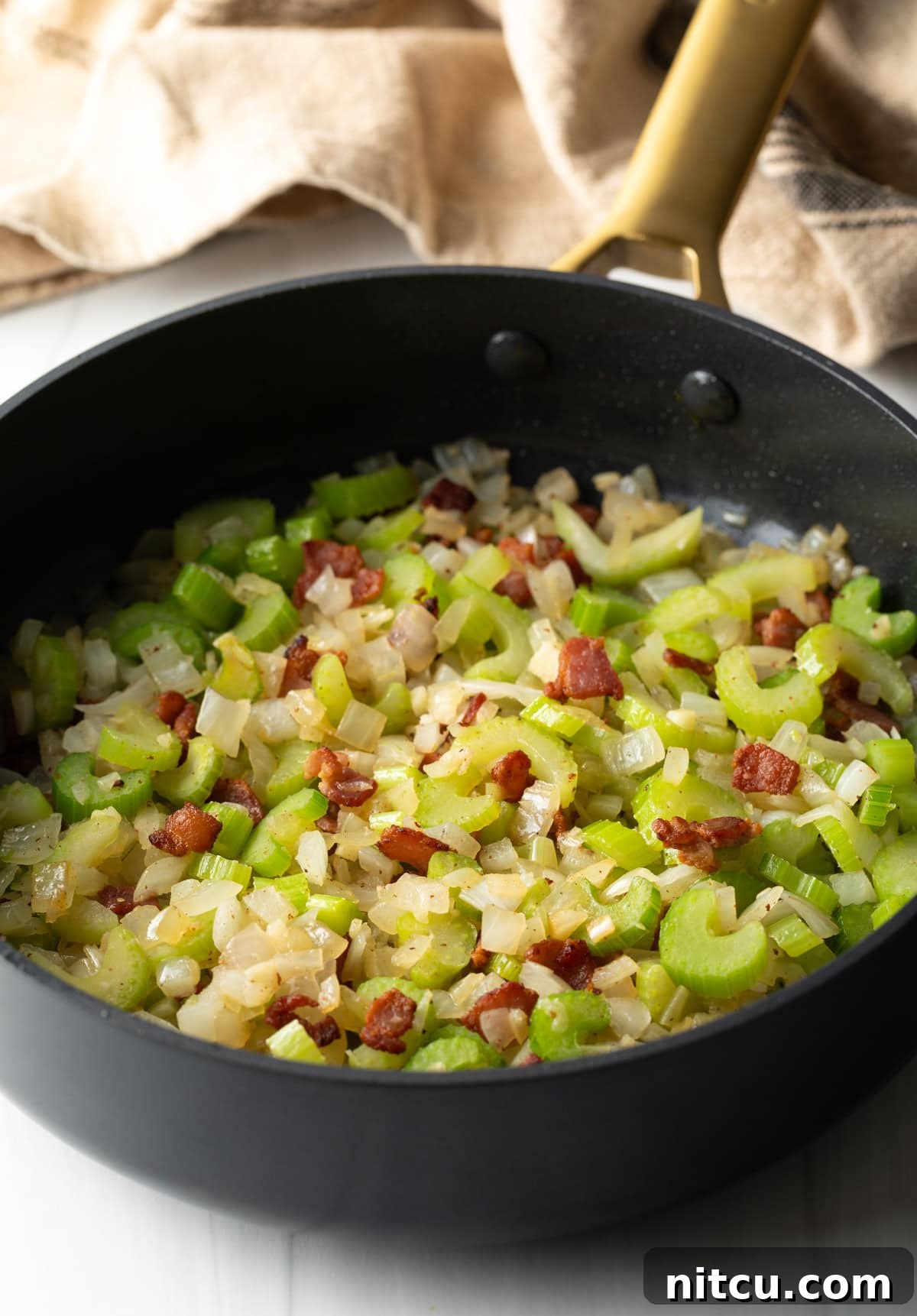 Soul-Satisfying Slow Cooker Chicken Stew 6 Sautéing diced bacon, celery and onions in a large black pan.